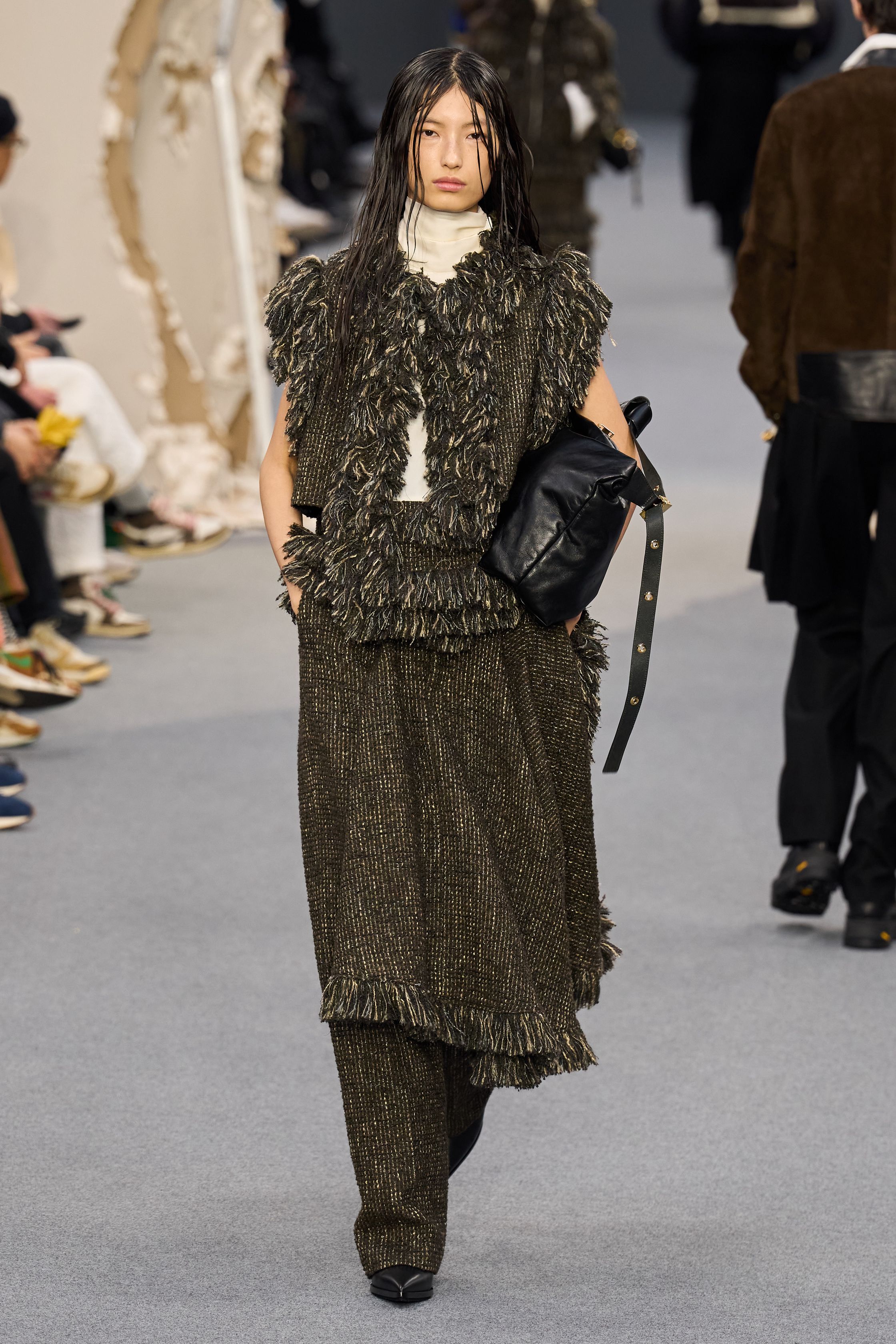 Sacai 2026秋冬再次展示其无可复制的“混合美学”。正装、牛仔、皮草与制服元素被高度结构化地拼接，形成既熟悉又陌生的服装形态。性别边界被进一步模糊，层叠结构制造流动节奏，使行走本身成为设计的一部分。系列在秩序与混乱之间找到平衡，是Sacai 对当代复杂生活状态的持续回应-顽石频道趋势研究